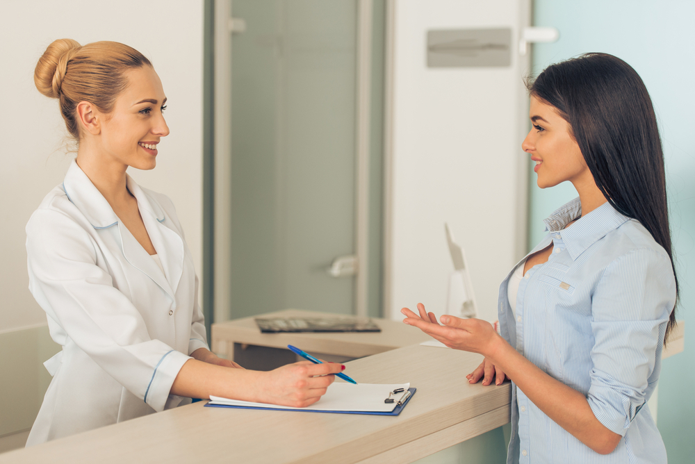 female doctor talking with patient standing in waiting room of the clinic