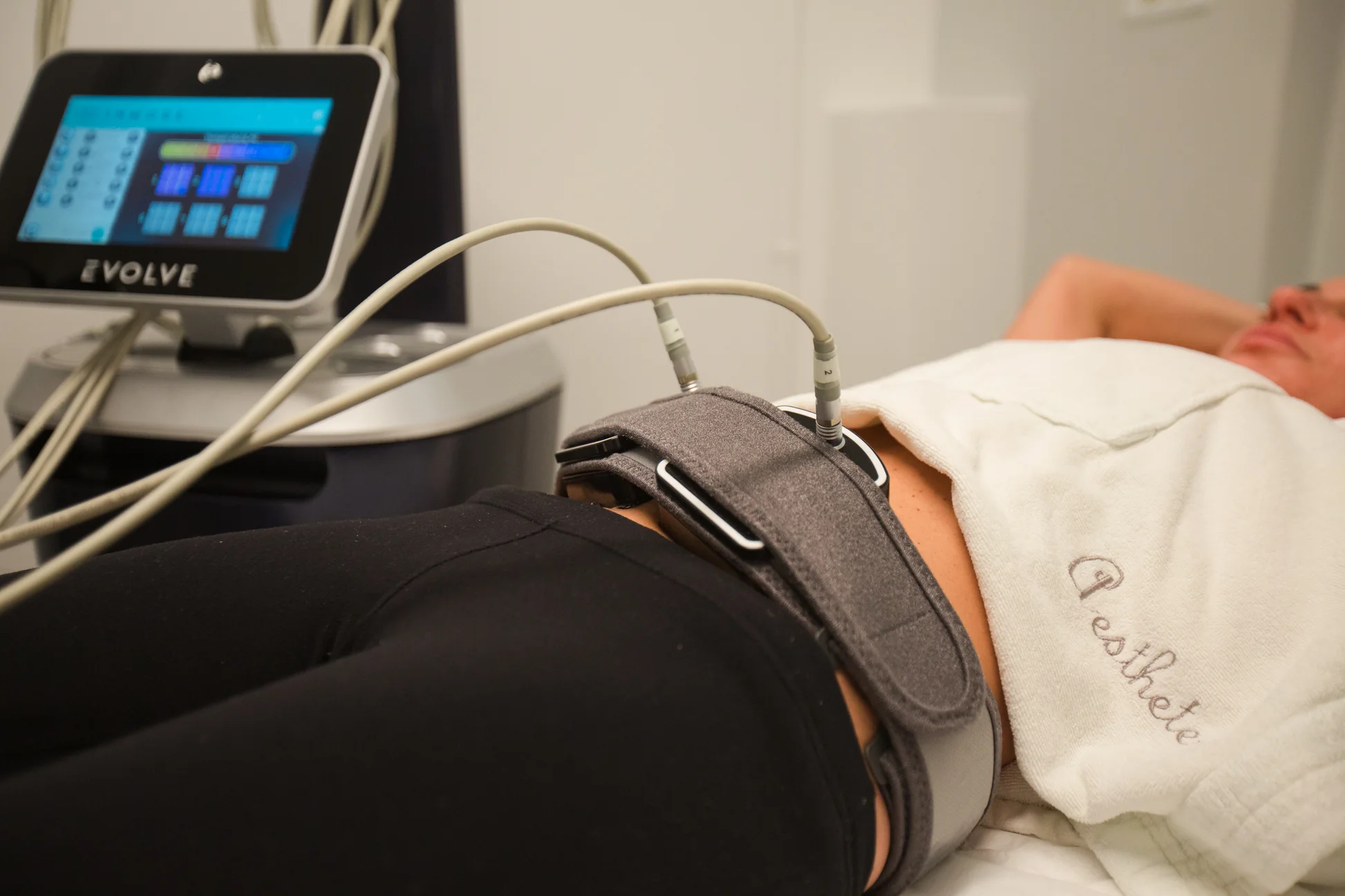 Patient undergoing Evolve fat reduction treatment with advanced device technology, targeting non-invasive body contouring