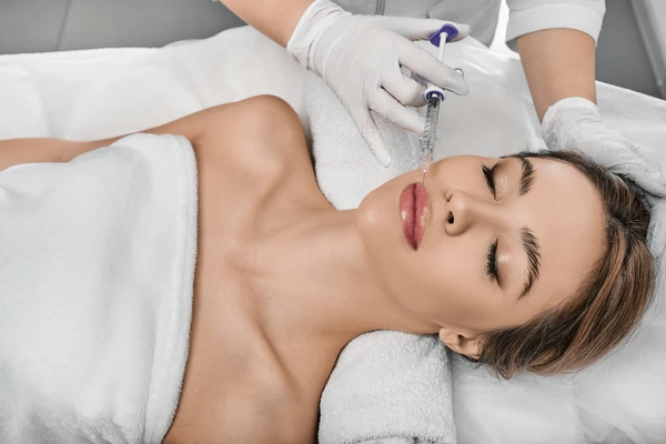 Patient receiving Restylane Kysse treatment for natural lip enhancement and hydration during a professional procedure
