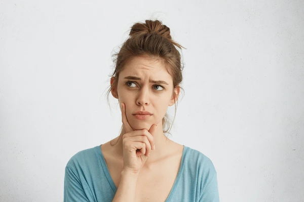 Young woman thinking if she is a good candidate for LED LightStim therapy, considering her skincare and treatment options