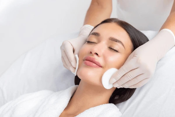 Beautician performing gentle skin cleansing as part of aftercare and recovery following LED LightStim therapy session