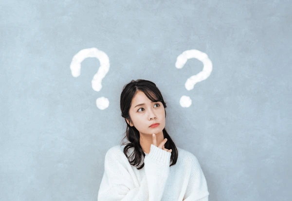 Woman considering her eligibility for QuantumRF InMode treatment with question marks symbolizing candidacy evaluation.