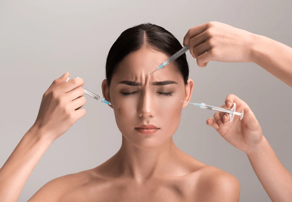 Woman frowning while receiving injections, illustrating potential side effects and risks of Xeomin treatment
