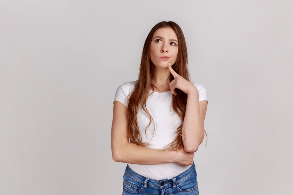 Young woman thinking about whether she is a good candidate for TempSure RF treatment.
