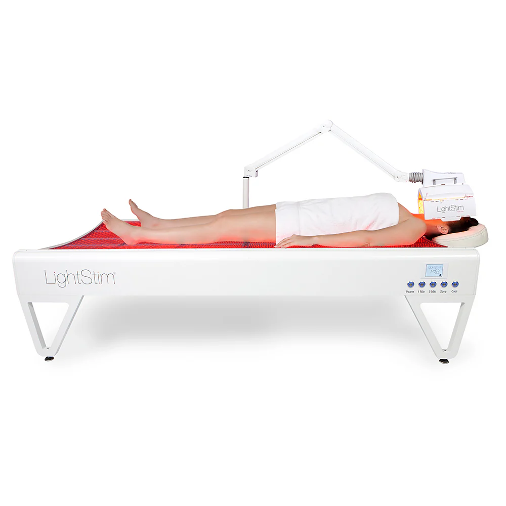 Patient receiving full-body LED LightStim therapy on specialized bed for skin rejuvenation