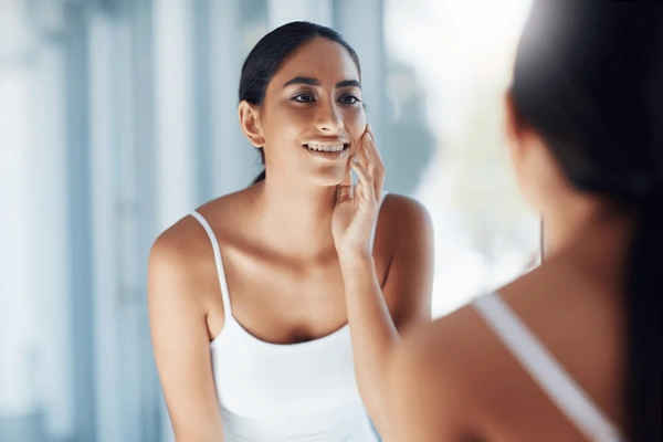 Woman examining smooth skin after Vivace treatment, showcasing aftercare and recovery benefits for radiant skin