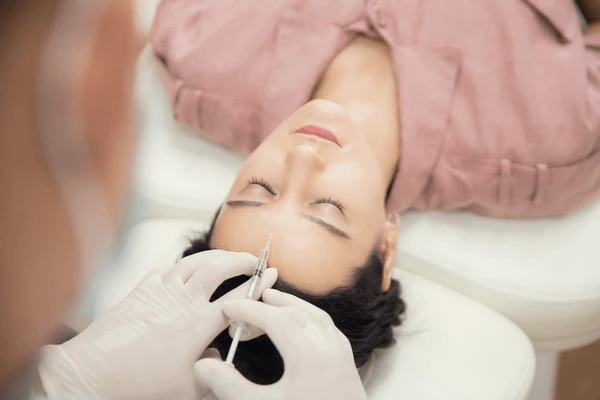 Woman receiving Xeomin frown line filler injection to smooth wrinkles and enhance facial appearance
